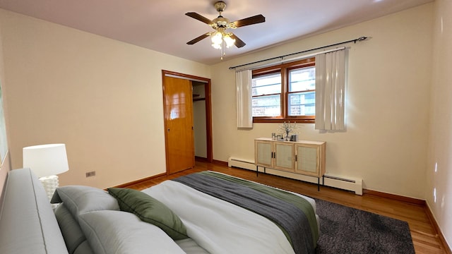 bedroom featuring baseboard heating, ceiling fan, a closet, and light wood-type flooring