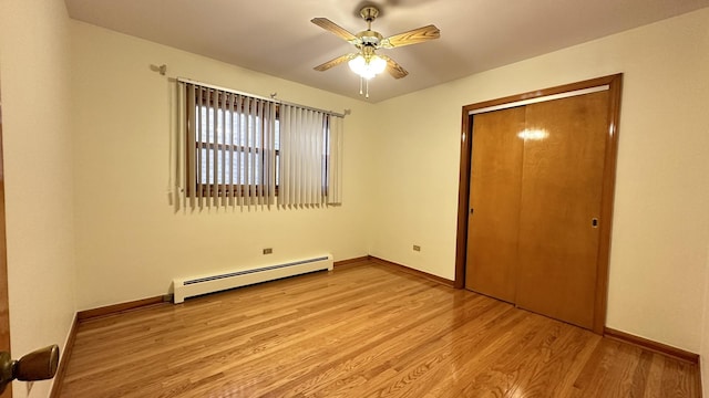 unfurnished bedroom featuring light hardwood / wood-style flooring, a closet, a baseboard heating unit, and ceiling fan