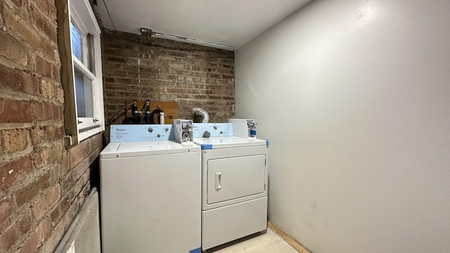 laundry room with brick wall and washing machine and clothes dryer