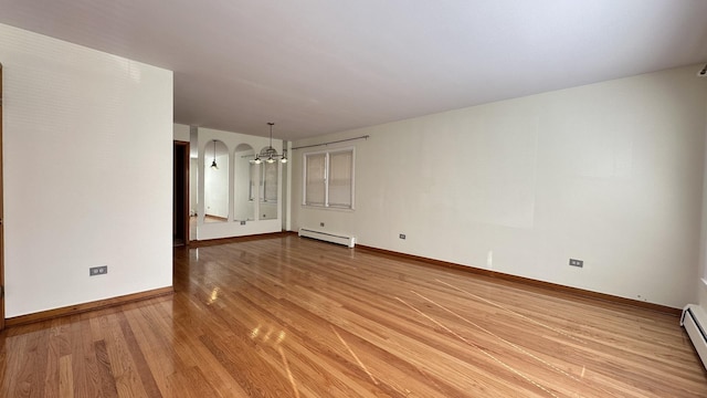 empty room featuring baseboard heating and light hardwood / wood-style floors