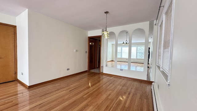 unfurnished dining area featuring a baseboard radiator and light hardwood / wood-style floors