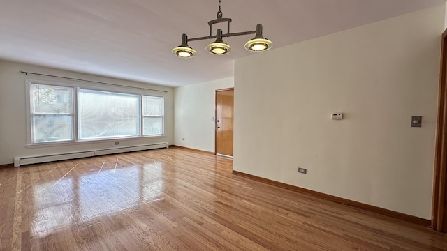 unfurnished room featuring baseboard heating and light wood-type flooring