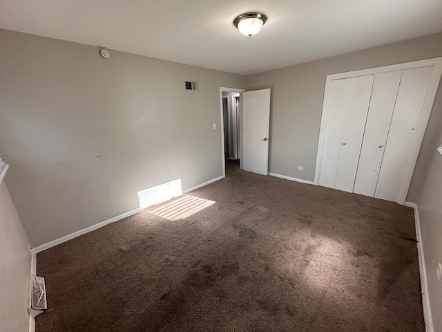 unfurnished bedroom featuring a closet and dark carpet