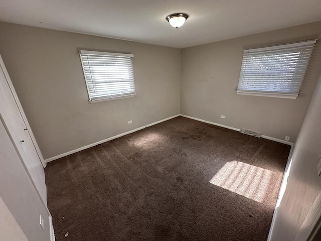 spare room featuring dark carpet