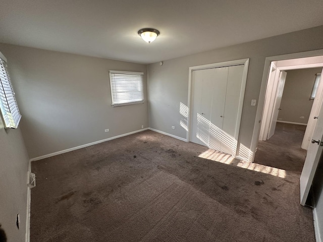 unfurnished bedroom featuring dark carpet and a closet