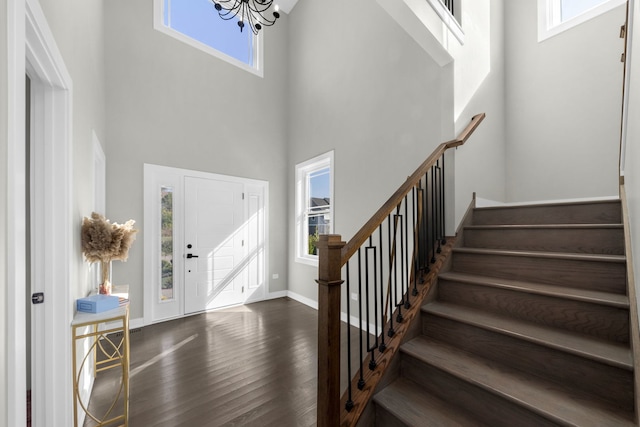 entryway with a high ceiling, dark hardwood / wood-style flooring, and an inviting chandelier