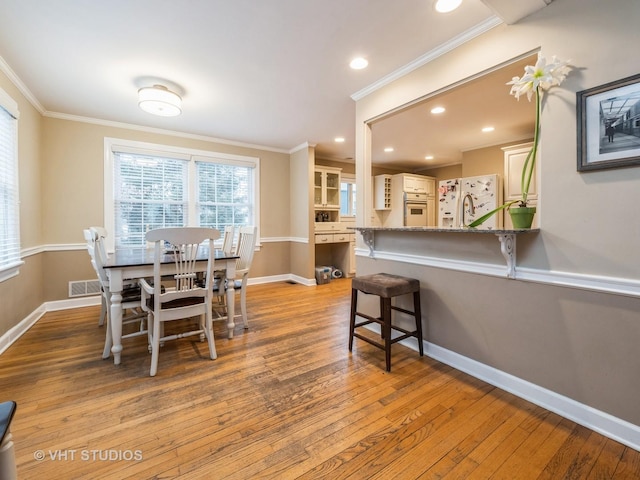 dining room with crown molding, sink, and light wood-type flooring