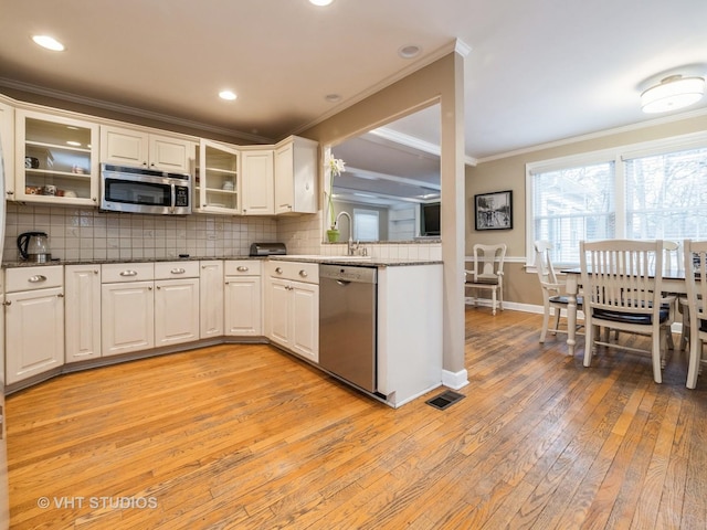 kitchen with white cabinets, appliances with stainless steel finishes, and light wood-type flooring