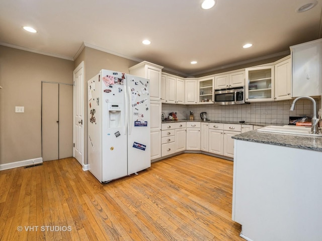 kitchen featuring sink, light hardwood / wood-style flooring, white refrigerator with ice dispenser, decorative backsplash, and white cabinets