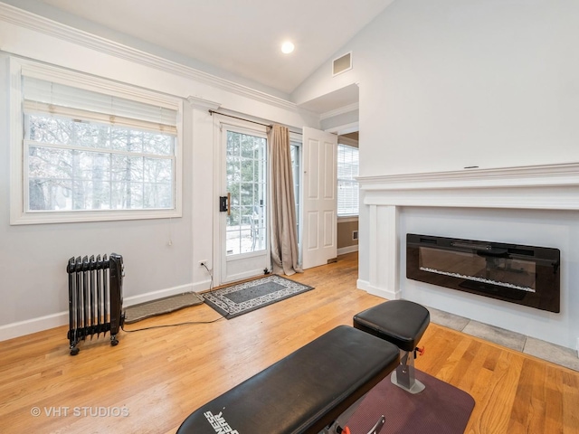 exercise room with hardwood / wood-style floors, radiator heating unit, and vaulted ceiling