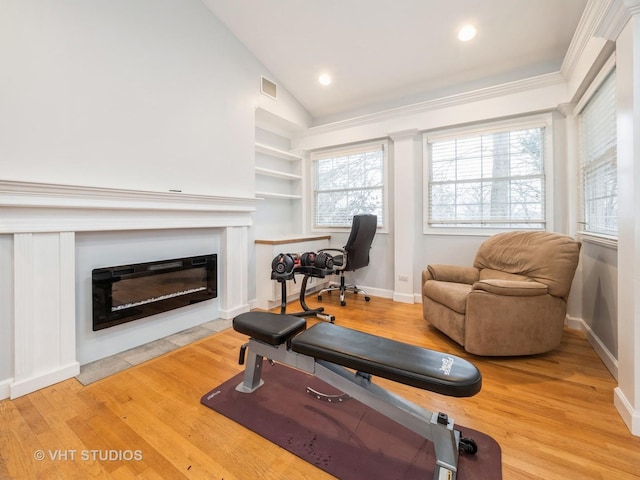 exercise room featuring built in shelves, wood-type flooring, lofted ceiling, and crown molding