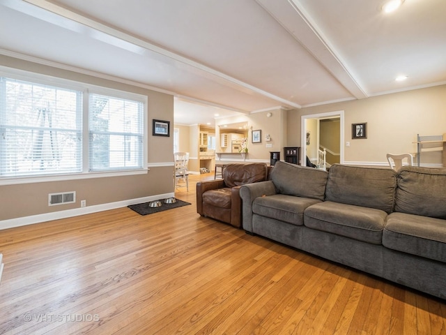 living room featuring beam ceiling, ornamental molding, and light hardwood / wood-style flooring