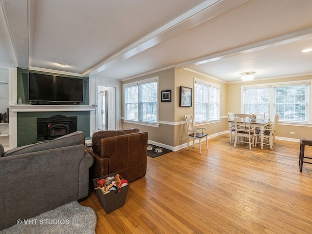 living room featuring light hardwood / wood-style floors, a wood stove, and ornamental molding