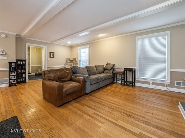 living room featuring beam ceiling, ornamental molding, and light wood-type flooring