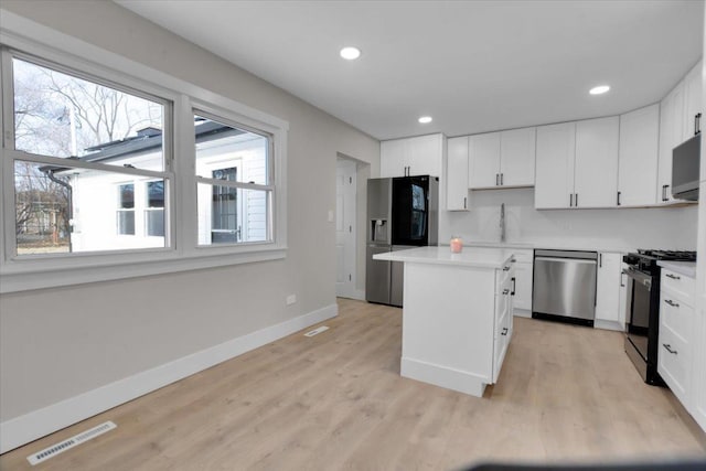 kitchen featuring light hardwood / wood-style floors, a center island, white cabinetry, and stainless steel appliances