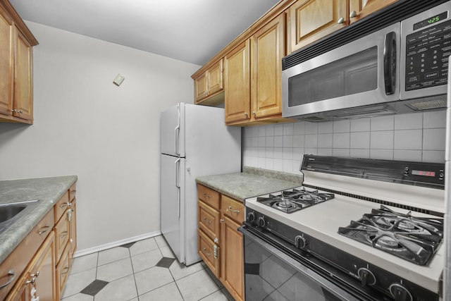 kitchen with backsplash, light tile patterned floors, and white appliances