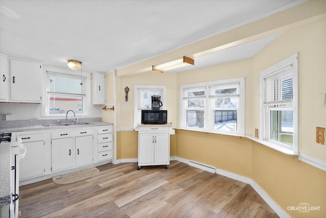 kitchen with backsplash, sink, white cabinets, range, and light hardwood / wood-style floors