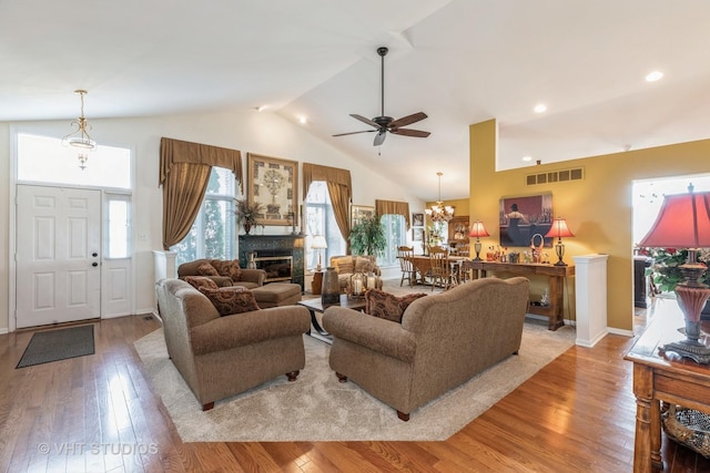 living room featuring ceiling fan with notable chandelier, light wood-type flooring, and high vaulted ceiling