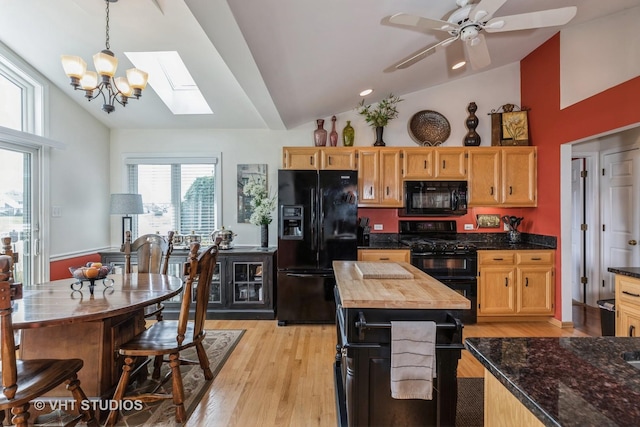 kitchen featuring pendant lighting, lofted ceiling with skylight, black appliances, ceiling fan with notable chandelier, and light hardwood / wood-style flooring