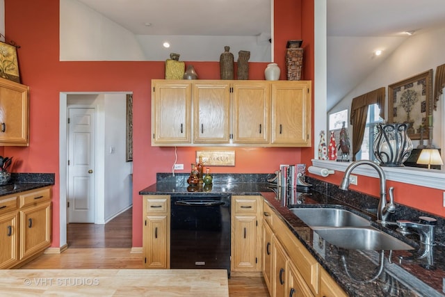 kitchen featuring dark stone countertops, dishwasher, vaulted ceiling, and sink