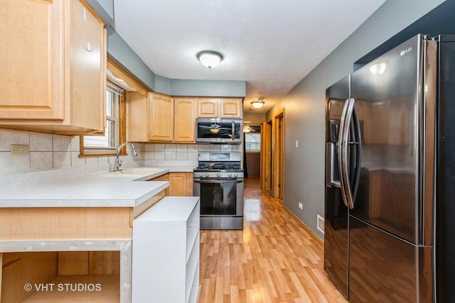 kitchen with light brown cabinets, appliances with stainless steel finishes, and tasteful backsplash