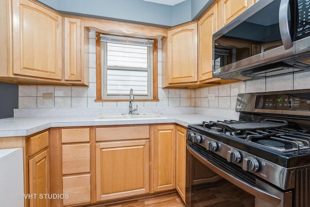 kitchen with light brown cabinets, black range with gas stovetop, sink, and tasteful backsplash