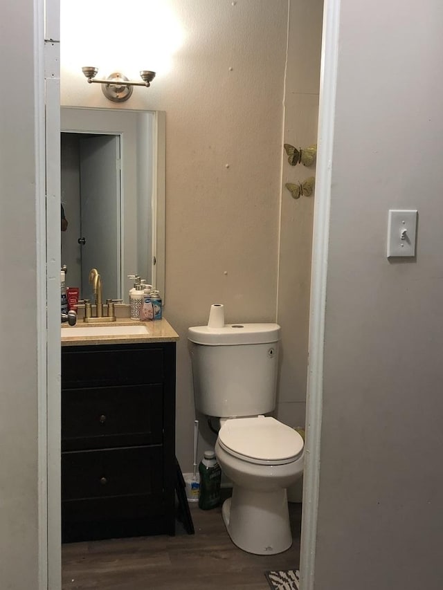 bathroom with toilet, vanity, and hardwood / wood-style flooring