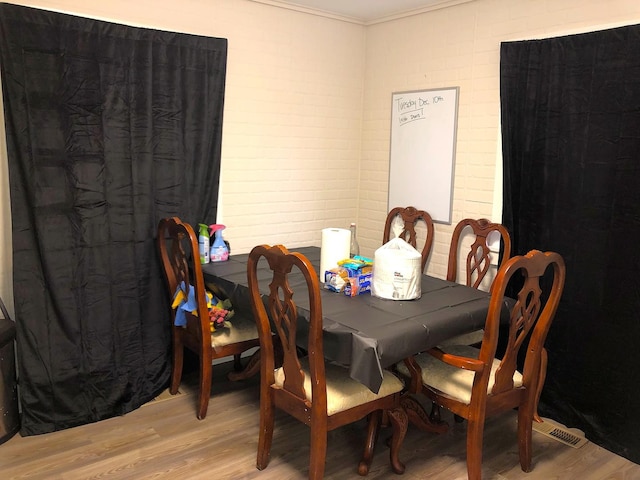 dining space with wood-type flooring and ornamental molding