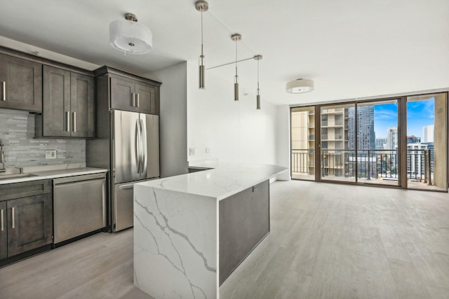 kitchen with light stone countertops, appliances with stainless steel finishes, backsplash, floor to ceiling windows, and pendant lighting