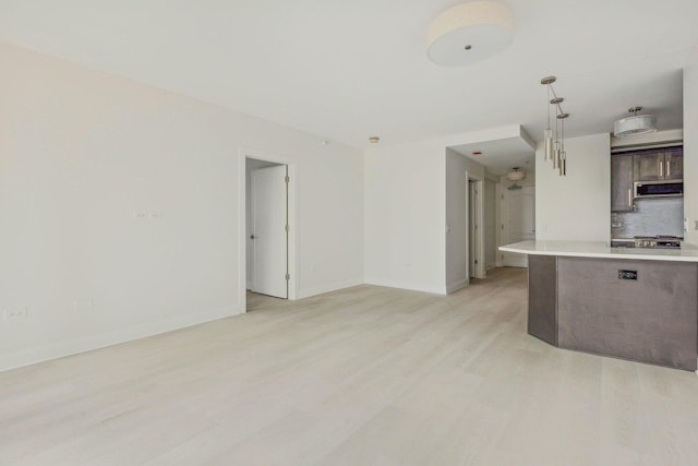 kitchen featuring dark brown cabinetry, hanging light fixtures, tasteful backsplash, light wood-type flooring, and range