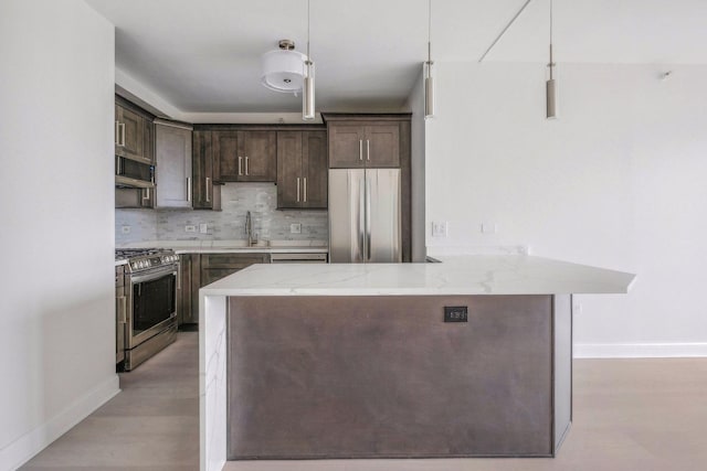 kitchen featuring pendant lighting, light stone countertops, sink, and appliances with stainless steel finishes