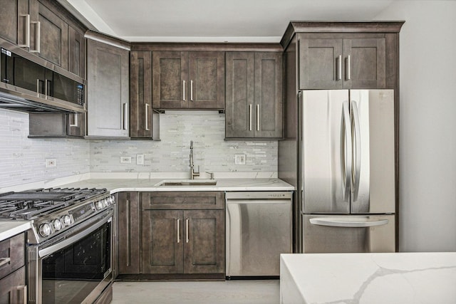 kitchen with backsplash, sink, light stone countertops, appliances with stainless steel finishes, and dark brown cabinetry