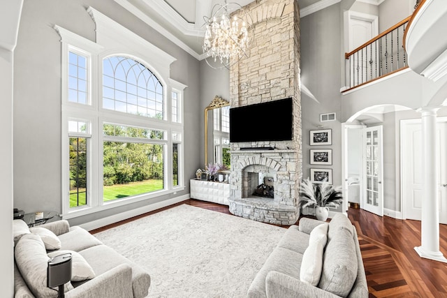 living room featuring dark hardwood / wood-style flooring, a fireplace, a towering ceiling, and a notable chandelier