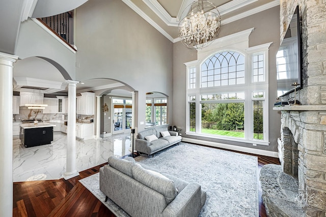 living room featuring a notable chandelier, ornate columns, and a high ceiling