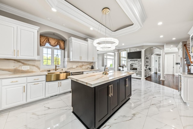 kitchen with white cabinetry, crown molding, hanging light fixtures, and ornate columns