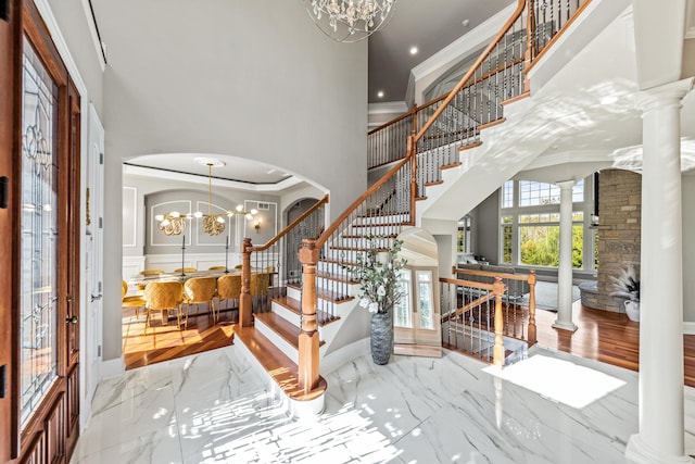 foyer featuring ornate columns, a chandelier, and ornamental molding