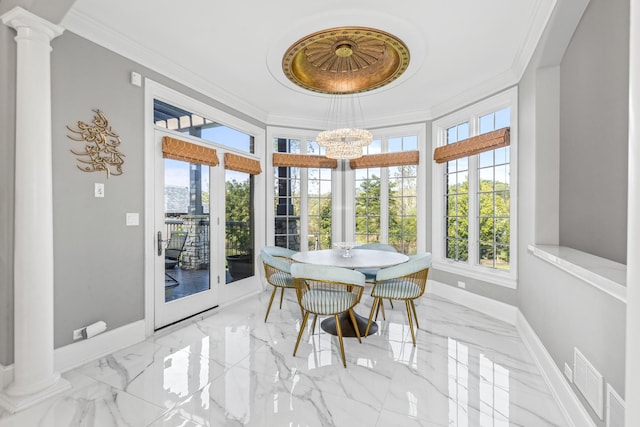 sunroom featuring decorative columns, plenty of natural light, and an inviting chandelier