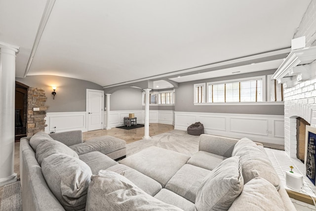 living room featuring a fireplace, decorative columns, and vaulted ceiling