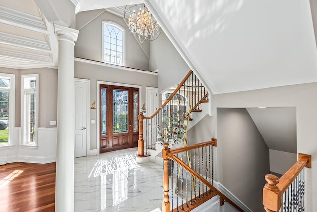 foyer entrance with ornate columns, a healthy amount of sunlight, and a chandelier