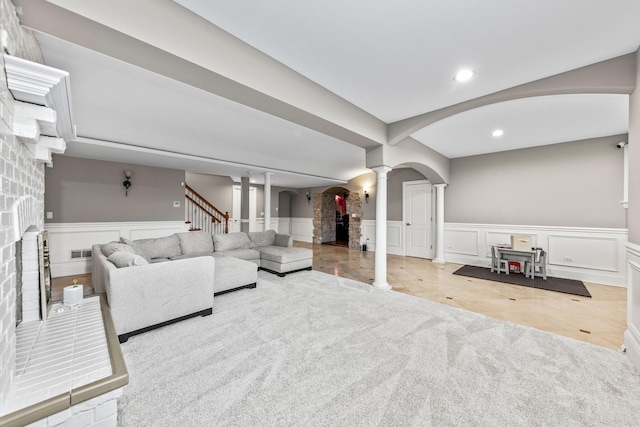 living room featuring decorative columns and a brick fireplace