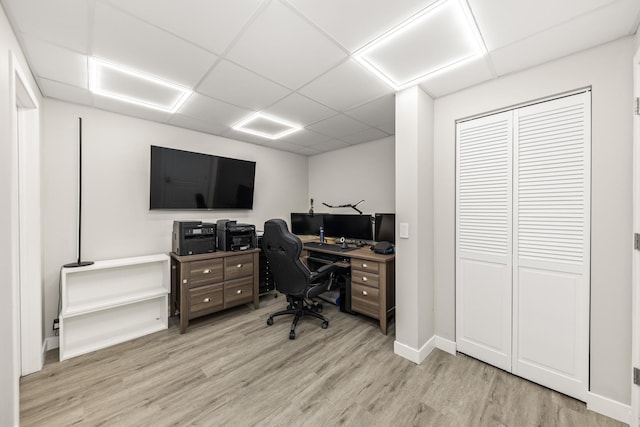 home office with a drop ceiling and light wood-type flooring