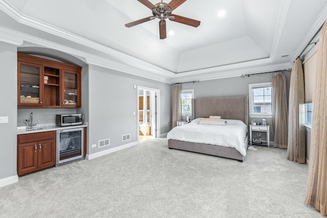 carpeted bedroom with sink, ceiling fan, connected bathroom, a tray ceiling, and beverage cooler