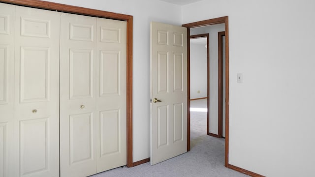 unfurnished bedroom with baseboards, a closet, and light colored carpet