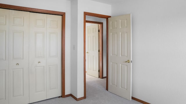 unfurnished bedroom with light carpet, a closet, and baseboards