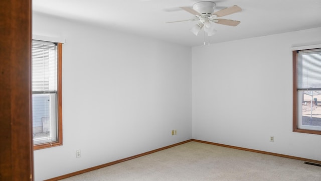 empty room featuring light colored carpet, visible vents, ceiling fan, and baseboards