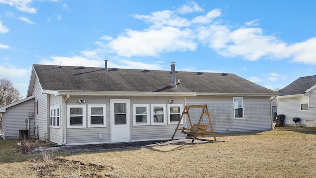 rear view of house with a shingled roof and a lawn