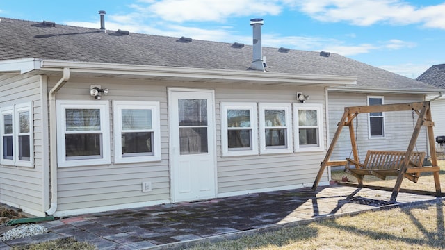 back of house with a shingled roof and a patio