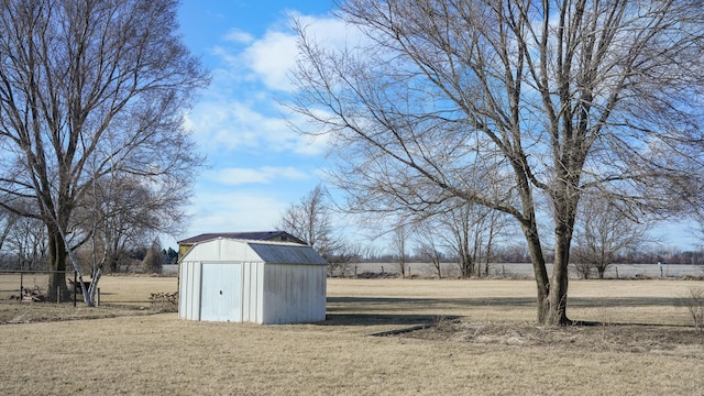 view of yard featuring an outbuilding, a storage unit, a rural view, and fence