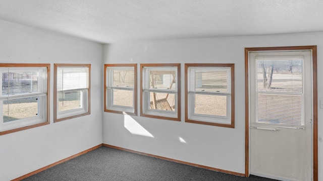 empty room featuring carpet, a textured ceiling, and baseboards