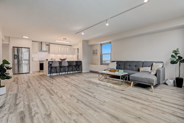 living room with light hardwood / wood-style floors and track lighting